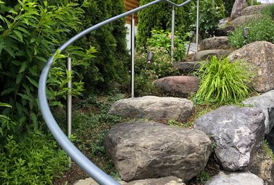 Geschwungener Handlauf an einer Natursteintreppe entlang - Bernet «Flexo Handläufe»