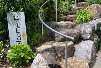 Geschwungener Handlauf an einer Natursteintreppe entlang - Bernet «Flexo Handläufe»