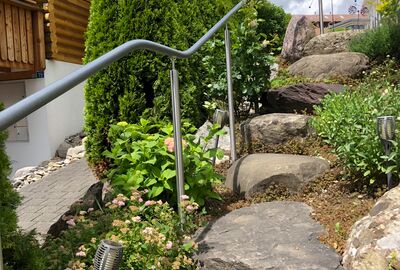 Geschwungener Handlauf an einer Natursteintreppe entlang - Bernet «Flexo Handläufe»